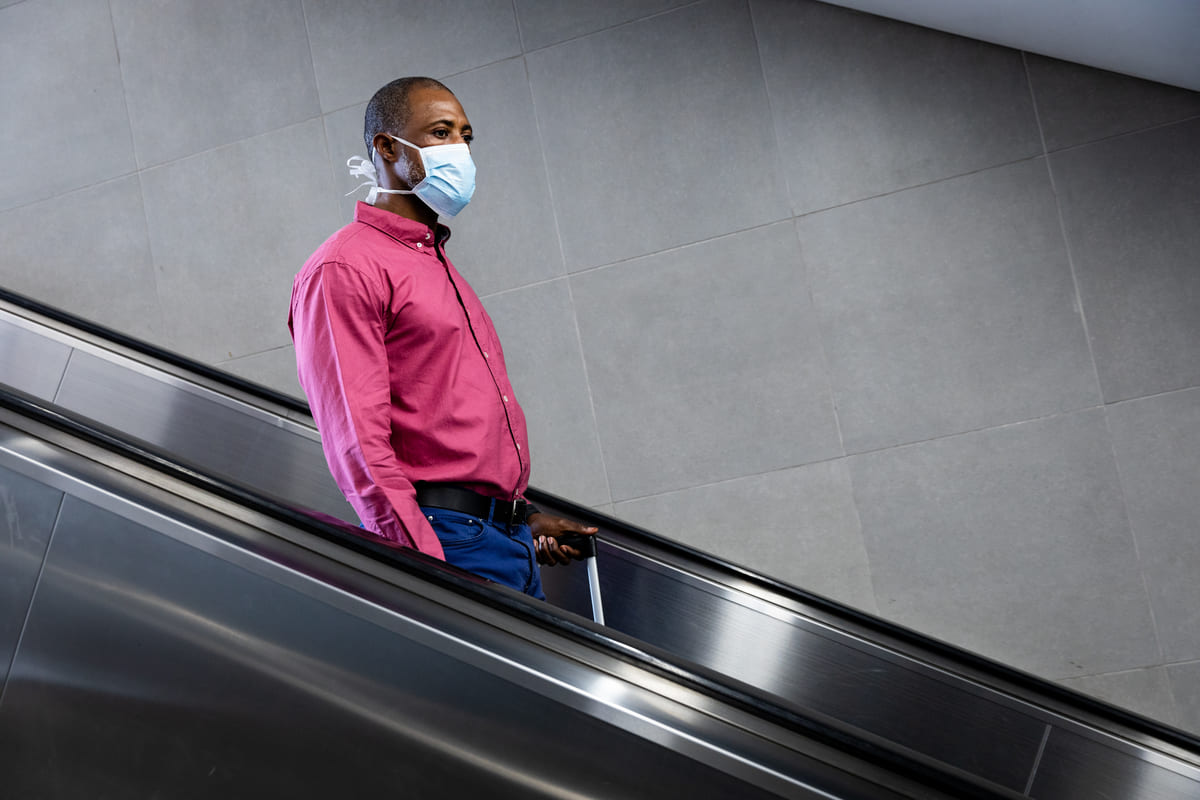 uomo sulle scale mobili con mascherina per coronavirus