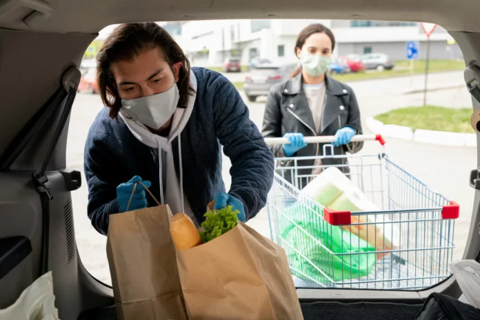 due persone con guanti monouso fuori supermercato